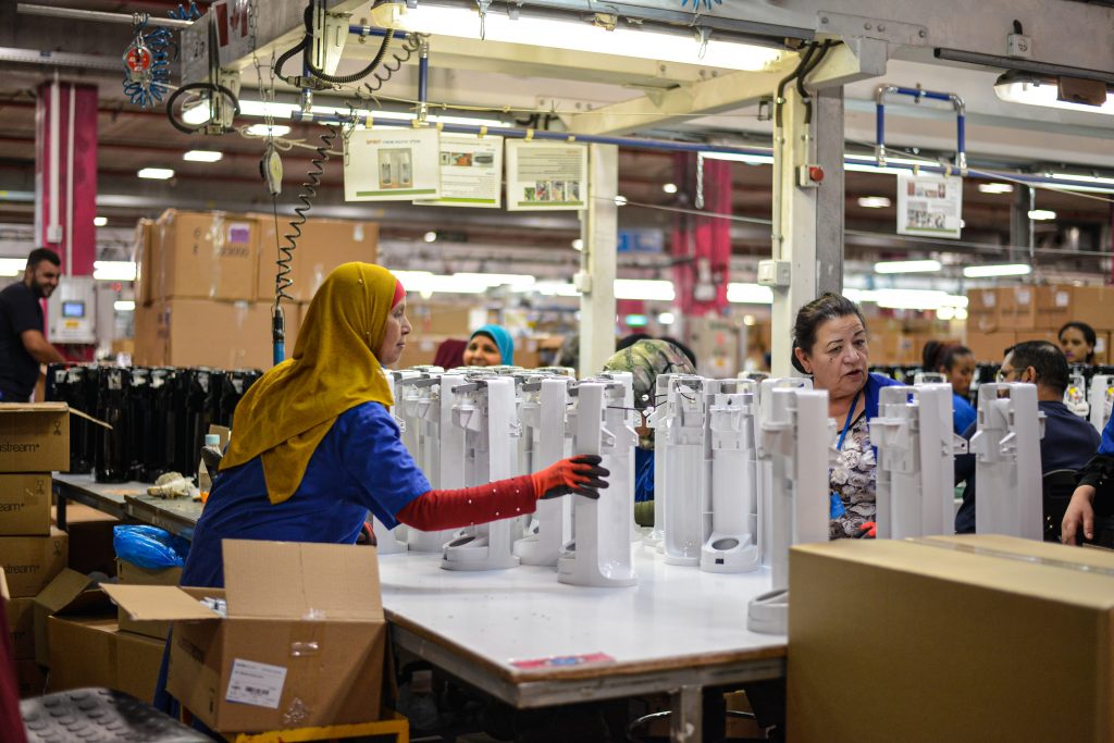 People working in a factory filling bottles.